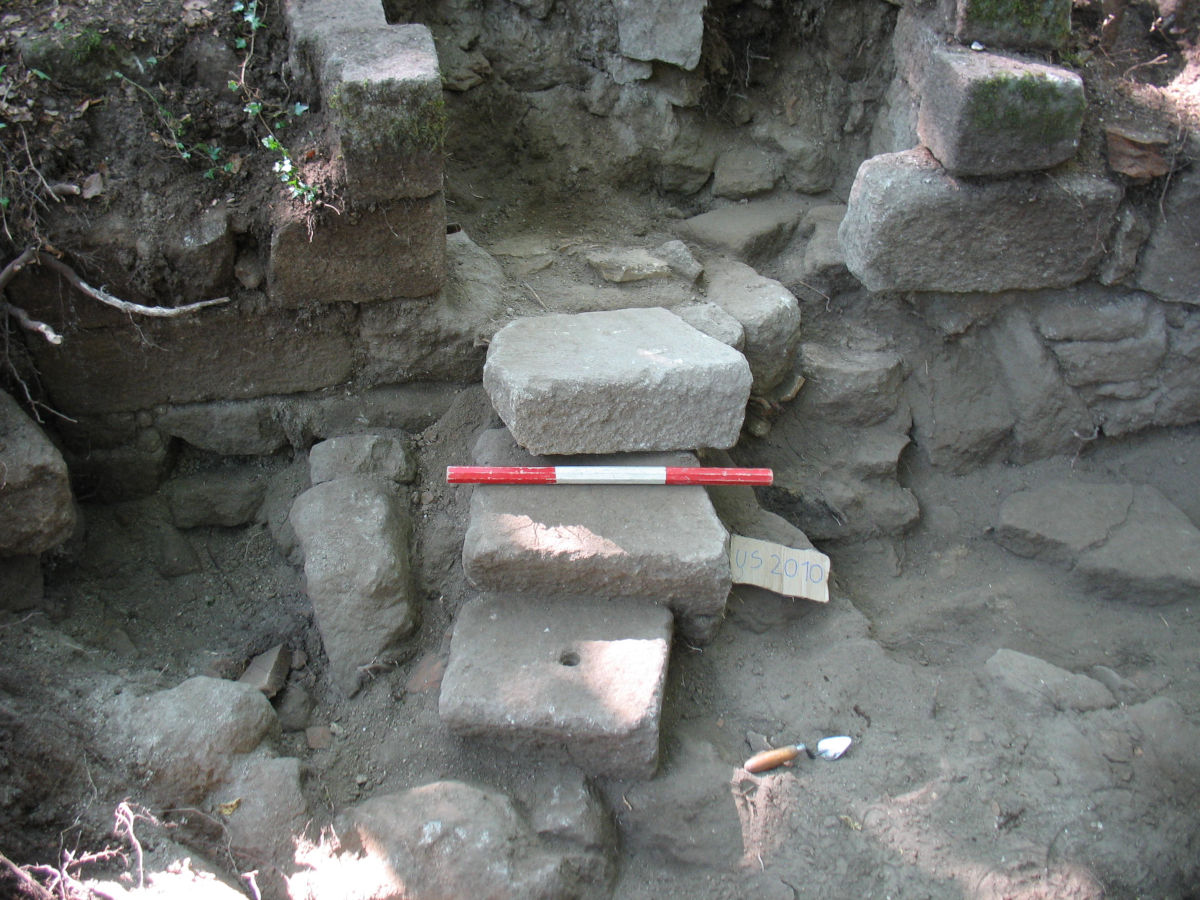 La foto mostra una scala fatta con materiale di riutilizzo su strati di crollo che indicano ulteriori frequentazioni del sito